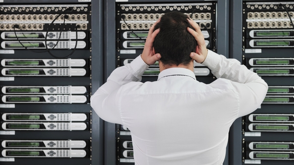 A server administrator with his back facing, frustrated with a server rack